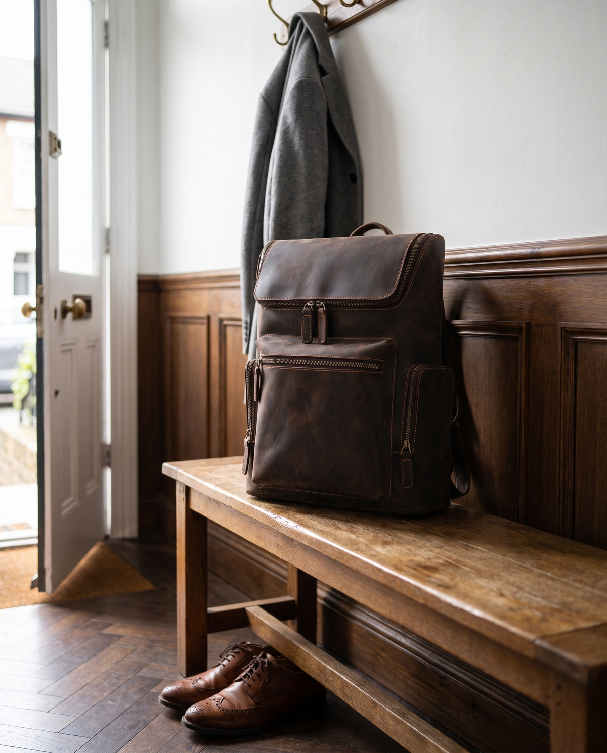 Velavio Atlas brown crazy horse leather backpack on a wooden hallway bench