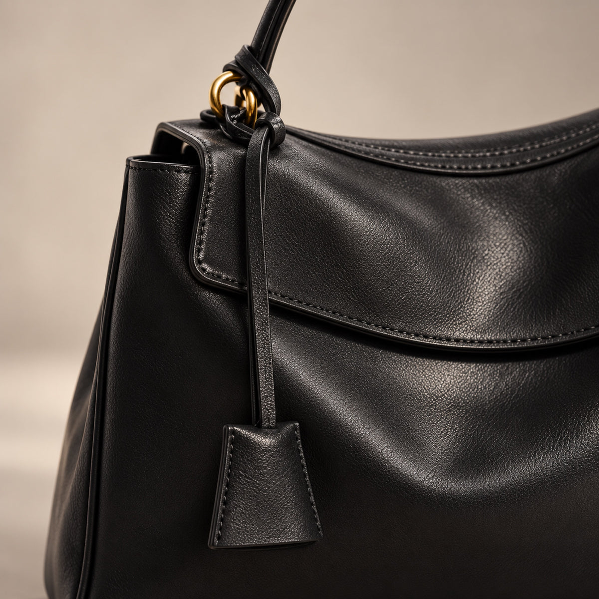 Close-up of the handle ring, leather tie and key tag on the Kensington bag