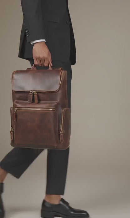 Man in a suit carrying the brown Crazy Horse leather flap laptop backpack by its top handle