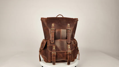 Brown leather drawstring buckle rucksack turning on a stand, showing the front buckle pockets and flap